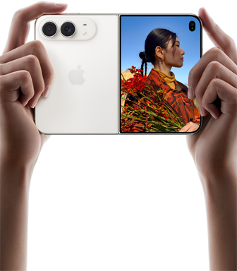 Due mani tengono un iPhone Duo bianco stellare in orizzontale, aperto; sul pannello sinistro si nota la doppia fotocamera posteriore Fusion da 48MP, mentre sul pannello destro si vede una persona che si fa fotografare sullo schermo esterno; il soggetto può vedere il proprio volto mentre viene scattata la foto grazie alla funzione Duo Preview