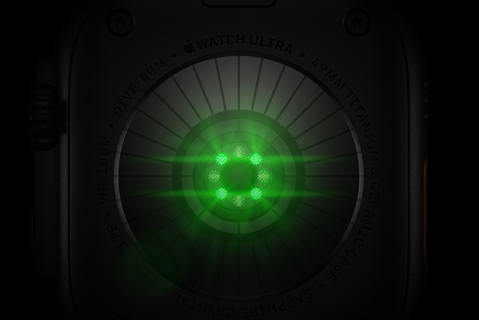 Un Apple Watch Ultra 4 mostrato da dietro, cassa in titanio nero, una serie di sensori rotondi con luci LED verdi che pulsano
